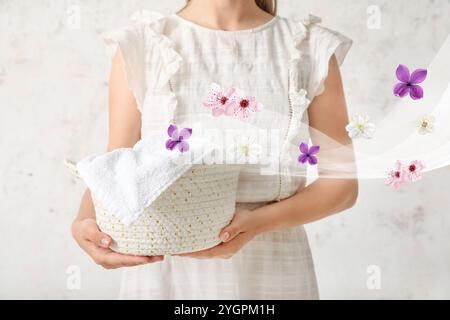 Woman holding basket of clean laundry on light background Stock Photo