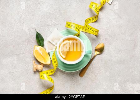 Cup of diet tea, lemon and measuring tape on grunge background. Weight loss concept Stock Photo