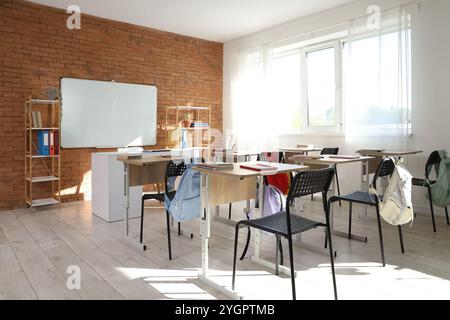 Interior of empty classroom with whiteboard, desks and shelf units Stock Photo