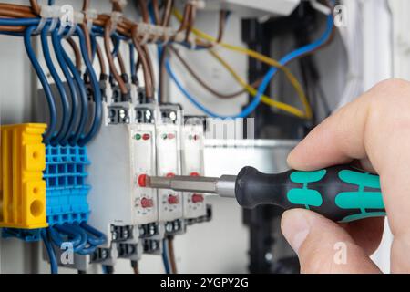 Hand Using Screwdriver on Electrical Terminal Block Stock Photo