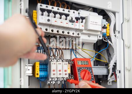 Hands Using Multimeter for Electrical Testing in Panel Stock Photo