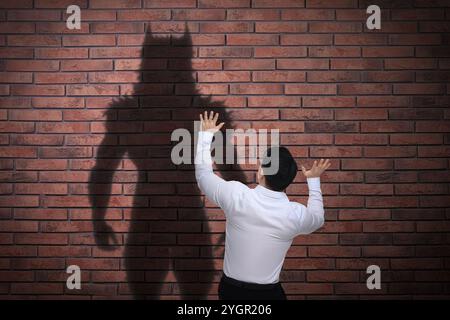 Man scared by monster. Scary shadow on brick wall Stock Photo