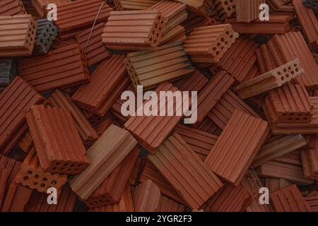 A mountain of red and brown clay bricks on a construction site. A close-up of the texture showing the building materials used in masonry and construct Stock Photo