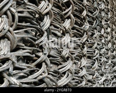 An intricately woven natural fence background. Old rustic fence texture made from natural materials. Stock Photo