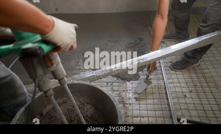 Pouring Self-Leveling Floors. Self-Leveling Floors On A Large Area, A Worker. Leveling with a mixture of cement floors. Workers pour self-leveling flo Stock Photo