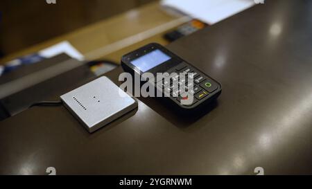 Terminal for paying for a hotel room. Hand terminal on the number at the reception desk. Close-up of a card payment terminal at a hotel counter. Stock Photo