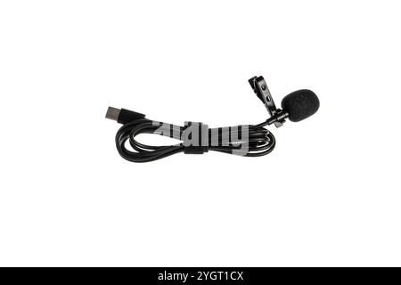 A black lavalier microphone with a foam windscreen and a USB-C connector, neatly coiled with a Velcro strap, isolated on a white background. Stock Photo