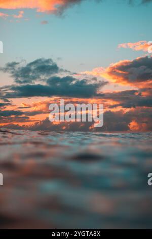 Stunning sunset clouds over the ocean in Waikiki, glowing with orange and pink hues. Stock Photo