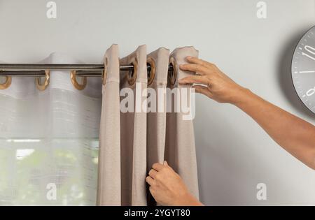 Worker repairman hanging and fixing the curtain on the window Stock Photo