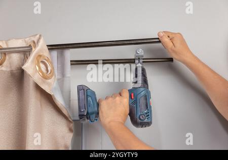 Worker repairman hanging and fixing the curtain on the window Stock Photo