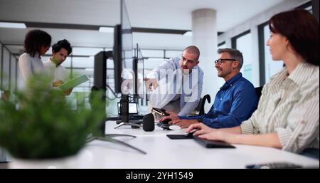 Businesspeople Analyzing Gantt Chart And Calendar On Computer In Office Stock Photo