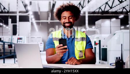 African Man Using Smartphone At American Plant. Stock Photo