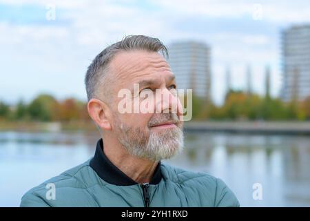 A mature man with a grey beard looks upwards with a thoughtful expression, adding a sense of introspection. Stock Photo