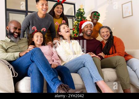 Diverse multiracial family laughing together on couch, celebrating christmas, at home Stock Photo