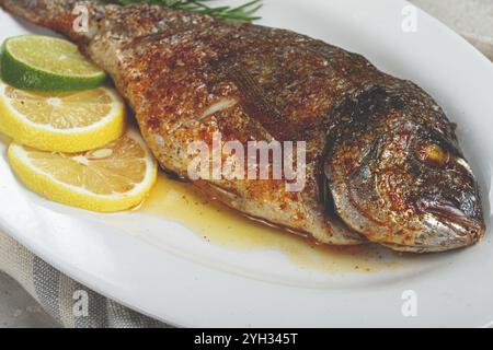 Baked dorado fish, in the oven, fried dorado, with spices and herbs, on a white plate, top view, homemade, no people Stock Photo