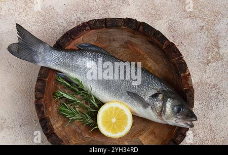 Fresh, raw sea bass fish, in a wooden plate, top view, no people Stock Photo