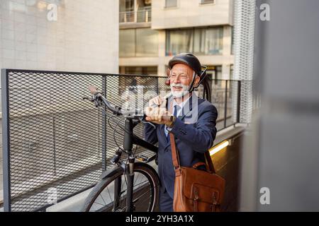 Confident senior businessman smiling and carrying bicycle on his shoulder while moving up in subway Stock Photo