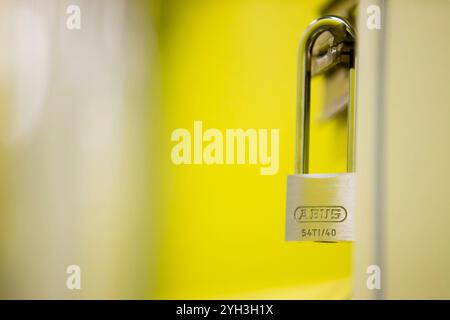 Close-up of a secure padlock on a yellow storage unit door, symbolizing safety and protection. Stock Photo