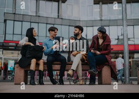 Young professionals having a lively conversation on a city bench Stock Photo