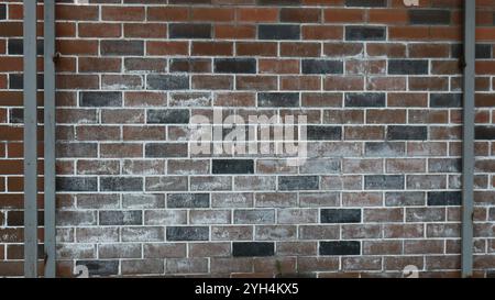 dark brick wall smeared in whitewash with gray vertical iron inserts as combined graphic urban empty background of brown brickwork Stock Photo