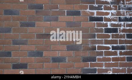 fragment of brick wall made of brown and black blocks with chaotic pattern of white keraska on the right side, urban geometric graphic resource Stock Photo