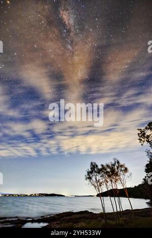 Stargazing of Milky Way over Lake Macquarie in Australia - blurry cloudy skies night landscape. Stock Photo