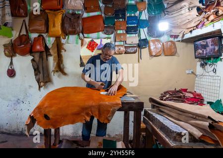 A man is cutting skin to make leather goods in a shop in Fez, Morocco. Stock Photo