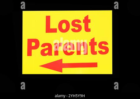 lost parents sign with left arrow red letters on yellow isolated on black background Stock Photo