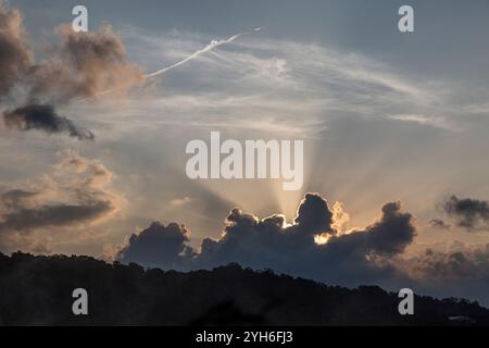 A dramatic sunset sky with sunburst rays of light coming forth from clouds at the bottom of image. Stock Photo