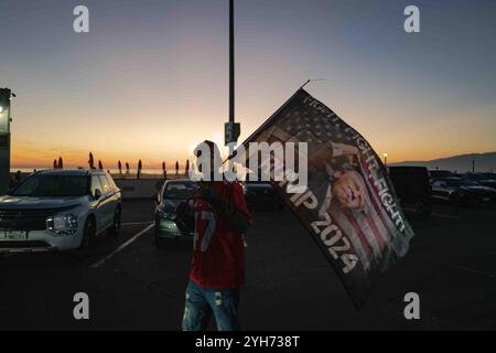 Santa Monica Beach, California, USA. 09th Nov, 2024. A large, enthusiastic crowd of Trump supporters gathers on Santa Monica Beach at sunset, waving American flags and cheering in celebration of the election results. The sky is painted with warm orange and pink hues, adding to the festive ambiance. Santa Monica Beach saw a gathering of Trump supporters celebrating his projected win in the 2024 U.S. presidential election. The event drew an enthusiastic crowd, as people waved flags, chanted slogans, and shared in the excitement. Credit: SOPA Images Limited/Alamy Live News Stock Photo