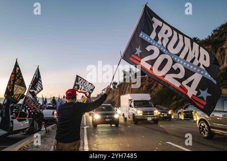 A large, enthusiastic crowd of Trump supporters gathers on Santa Monica Beach at sunset, waving American flags and cheering in celebration of the election results. The sky is painted with warm orange and pink hues, adding to the festive ambiance. Santa Monica Beach saw a gathering of Trump supporters celebrating his projected win in the 2024 U.S. presidential election. The event drew an enthusiastic crowd, as people waved flags, chanted slogans, and shared in the excitement. Organized spontaneously through social media, the celebration saw a mix of families, young supporters, and longtime back Stock Photo