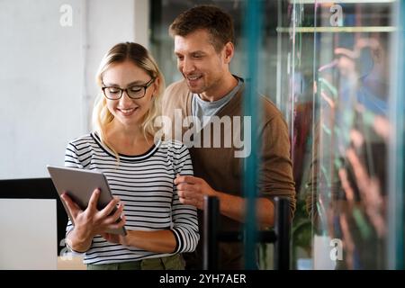 Two young businesspeople using a digital tablet while standing in a boardroom. Stock Photo