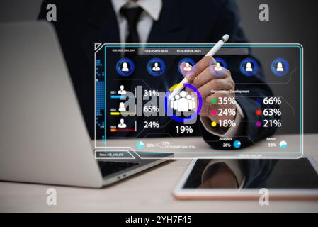 Businessman interacting with a virtual interface showing data analytics and human resource management dashboard, emphasizing technology in business op Stock Photo