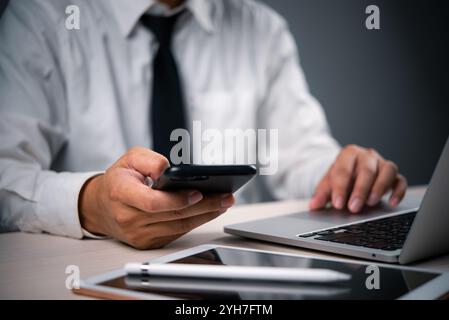 business professional multitasking using a smartphone and laptop, modern digital technology communication and multitasking in corporate environments. Stock Photo