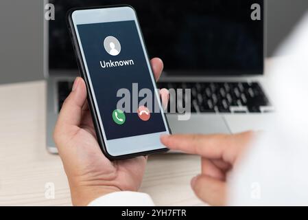 hand holding a smartphone displaying an incoming call from an unknown caller, representing communication, security risks, and mobile technology. Stock Photo