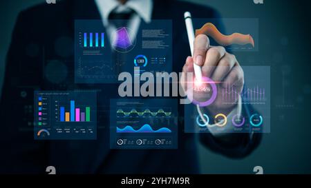 Business professional interacting with an advanced digital dashboard displaying various data analytics and performance metrics. Ideal for data analysi Stock Photo