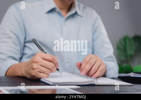 Business professional writing notes in a notebook. Ideal for themes around planning, strategy, or workplace organization in business environments. Stock Photo