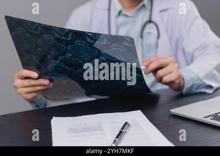 Doctor examining an X-ray image on a desk. Relevant for healthcare, medical diagnostics, radiology, and patient care content. Stock Photo