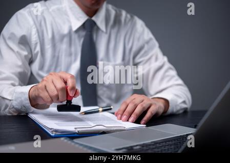 Business professional stamping a document for approval. Perfect for legal, contract, or official documentation themes in business settings. Corporate Stock Photo