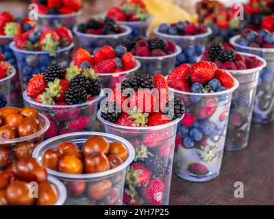 Close-up colorful mixed berry fruit Cups, red strawberries, blueberries, mulberry sale food in plastic cups in Georgia. Stock Photo