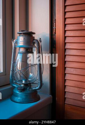 An old kerosene lamp on a windowsill in the rays of the setting sun Stock Photo