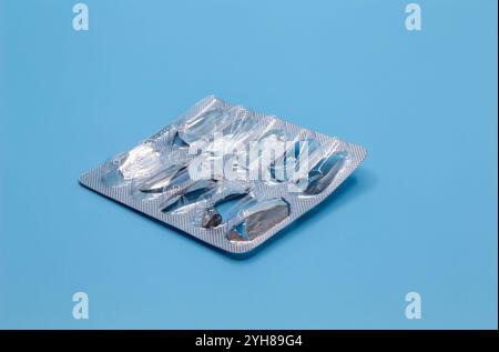 Empty blister pack from pills on a blue background. Focus on the foreground. Stock Photo
