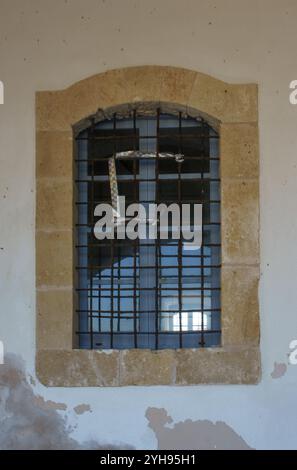 The old stone window frame features iron bars, highlighting a blend of architecture and nature light. Stock Photo