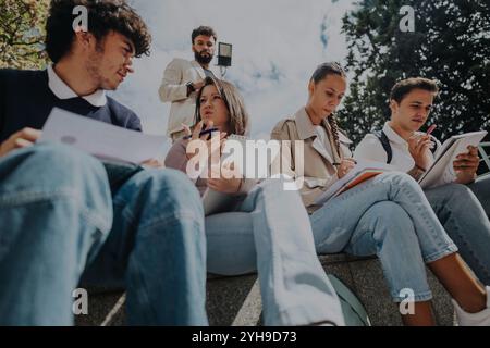 High school students collaborating outdoors with professor's guidance Stock Photo