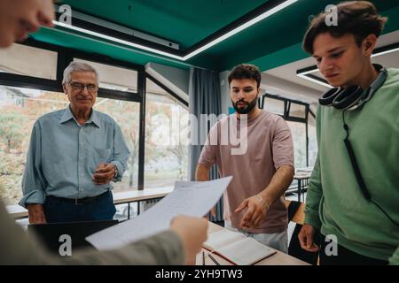 College students collaborating on a project with elderly professor guidance Stock Photo