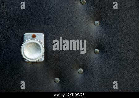 Old black door with leather upholstery on the cottage and door handle on the door, barn door as a background Stock Photo