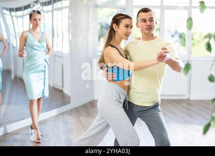 Couple practicing passionate tango guided by female dance instructor in studio Stock Photo