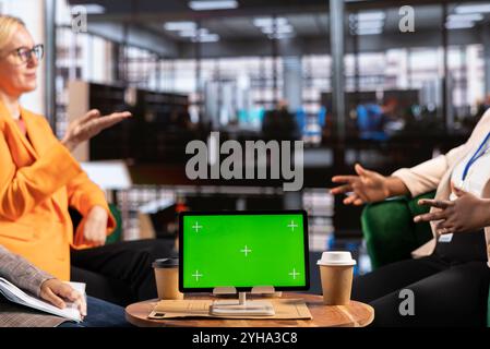 Multicultural team of specialists using mockup copy space in the office, working with resilience to accomplish enterprise objectives. Manager and employees meeting for a briefing. Stock Photo