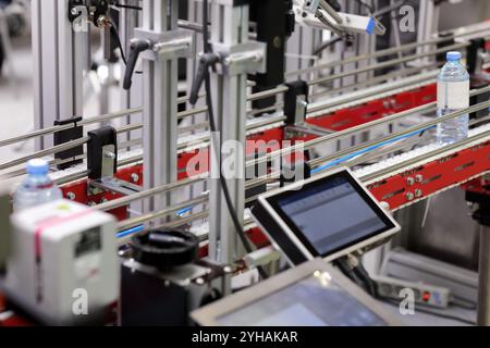 Conveyor system with touchscreen control panel in spring water bottling plant. Selective focus. Stock Photo