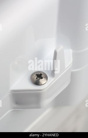 close-up of phillips crosshead screw head mounted on white textured plastic product or appliance surface, soft focus with copy space Stock Photo